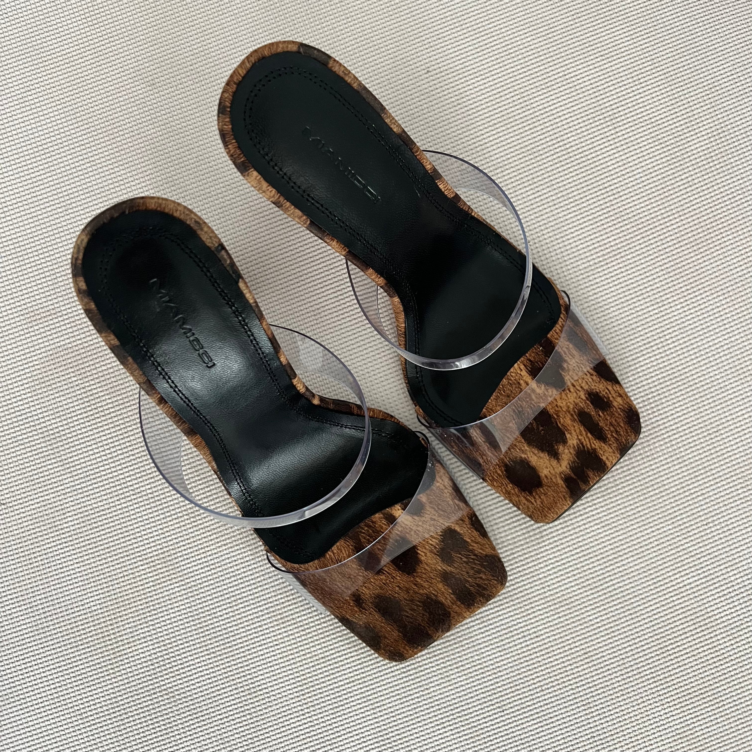 Vista frontal de la sandalia Babie Print: piel con estampado leopardo, tiras de vinilo transparente, tacón asimétrico