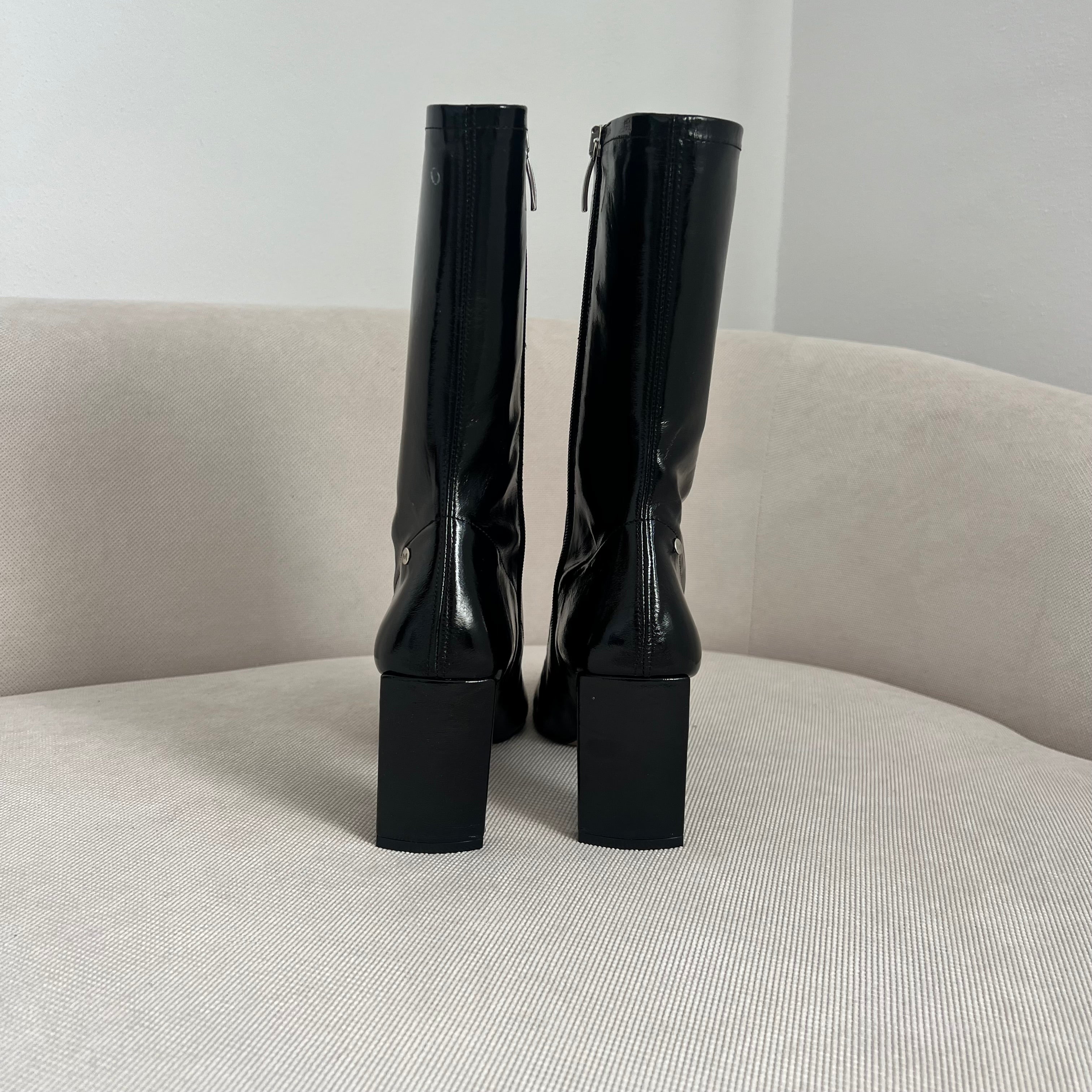 Detalle del tacón de 8 cm y parte trasera del botín PIZZO BLACK, destacando la ecopiel acharolada negra.